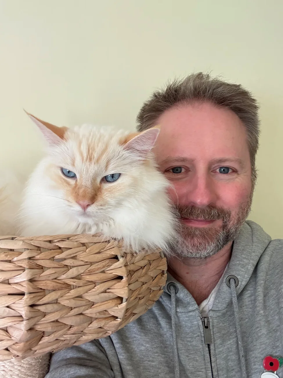 Alex from The Cotswold Cat Sitters beside a cream-coloured cat in a wicker basket